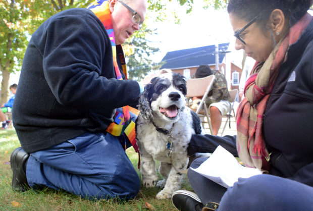 From left, Rev. Jeffrey A. Wargo blesses Cooper the dog as his owner, Calkins Media's Garden Minute host Tina Sottolano-Cain looks on during a blessing of pets ceremony Sunday, October 23, 2016 at St. Stephen's United Church of Christ in Perkasie, Pennsylvania. (Photo by William Thomas Cain)